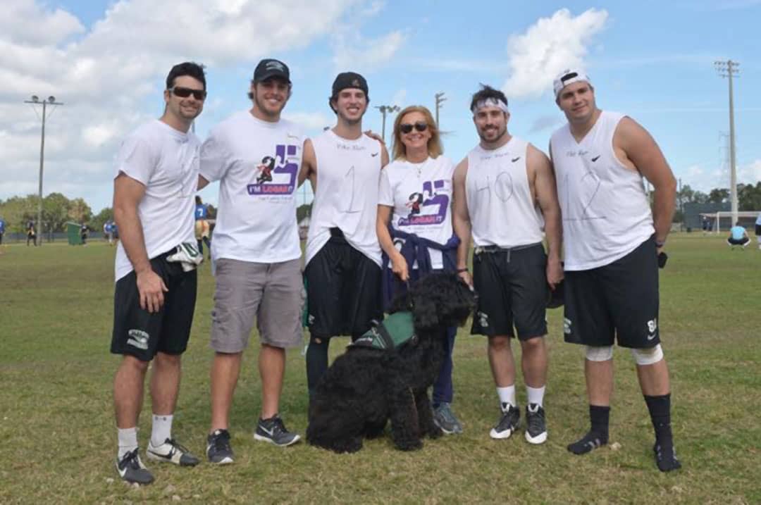 Five men with I’m Logan It founder P.A. Kushner and her service dog.
