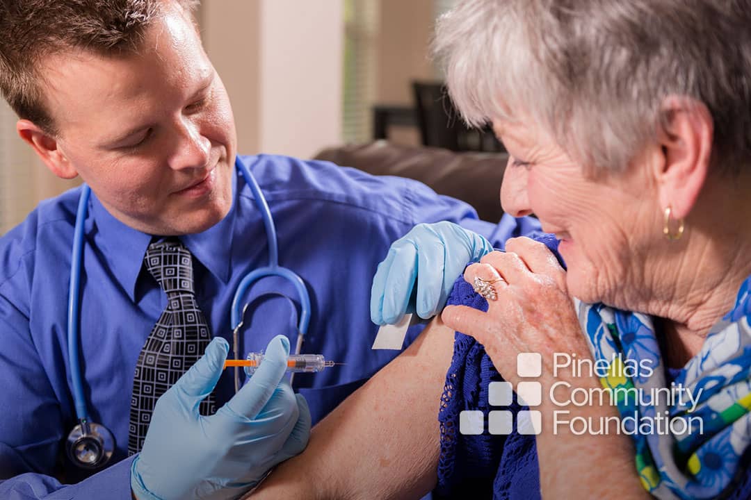 Doctor administers vaccine shot to elderly woman.