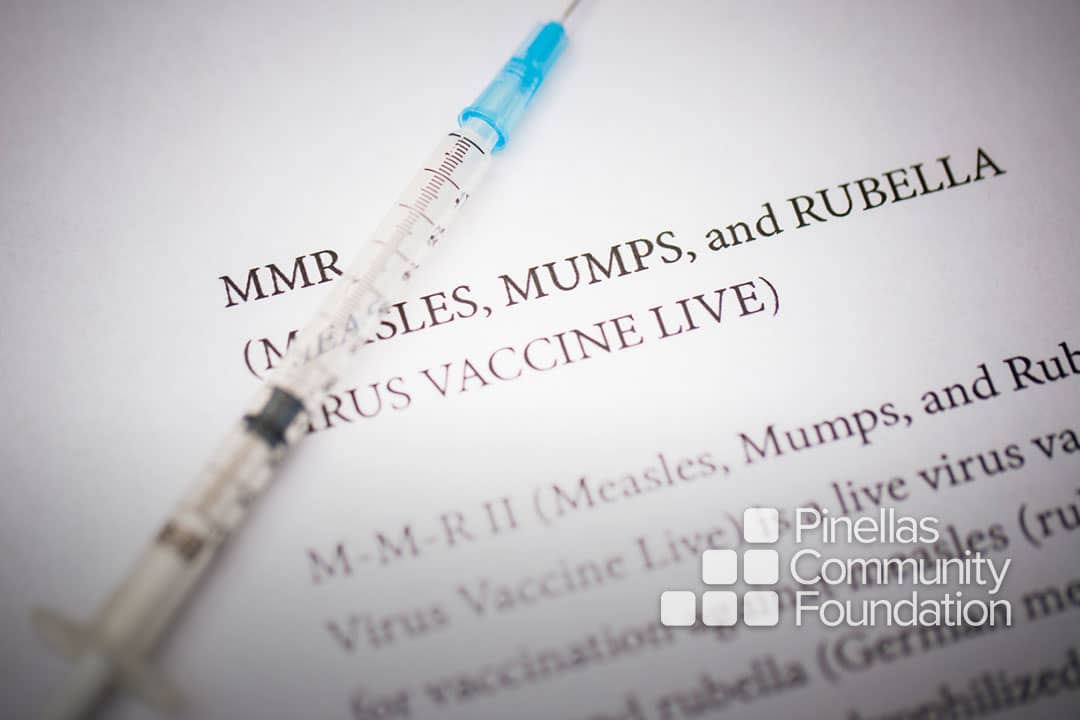 Syringe laying on MMR vaccine information sheet.