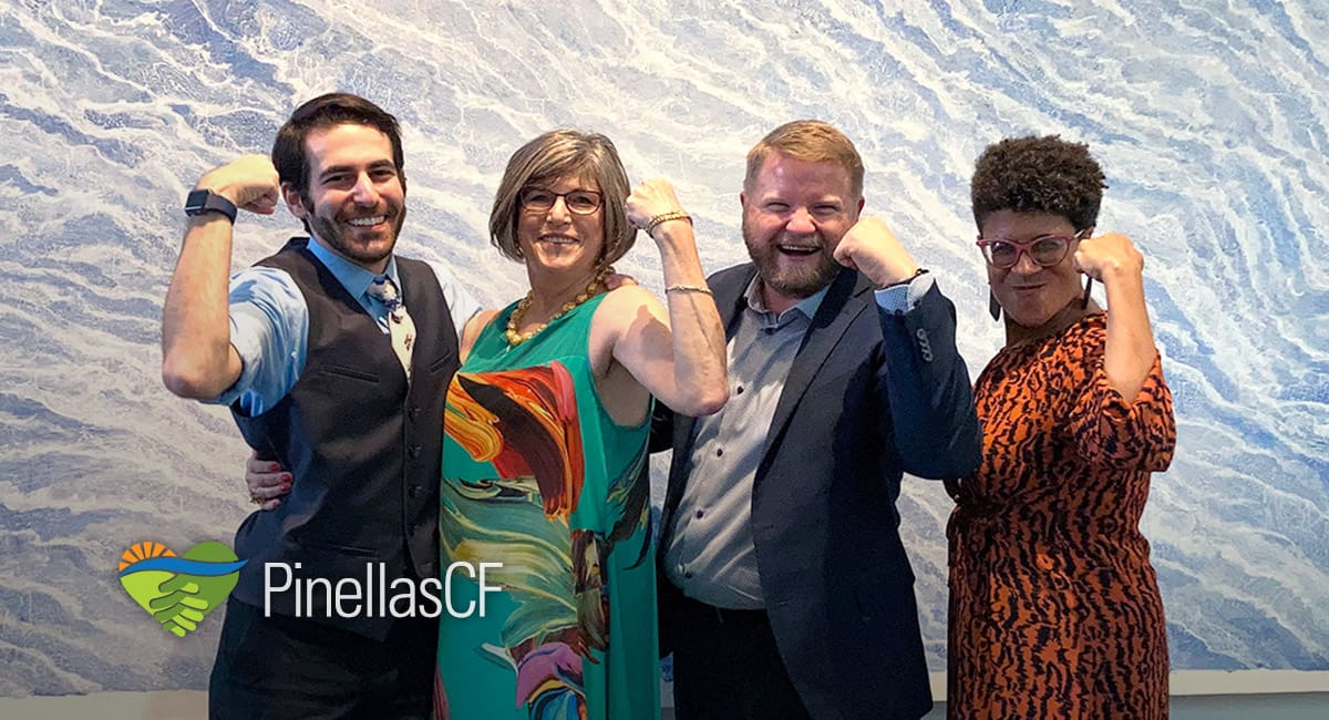 PCF staff members David Bender, Leah Slavensky, Duggan Cooley, and Leigh Davis flex their biceps in front of a painting at Leah's retirement party in Creative Pinellas, Largo.
