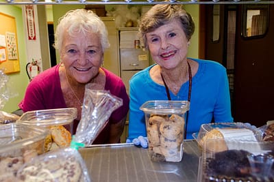 Two senior women enjoy volunteering at RCS Food Bank.